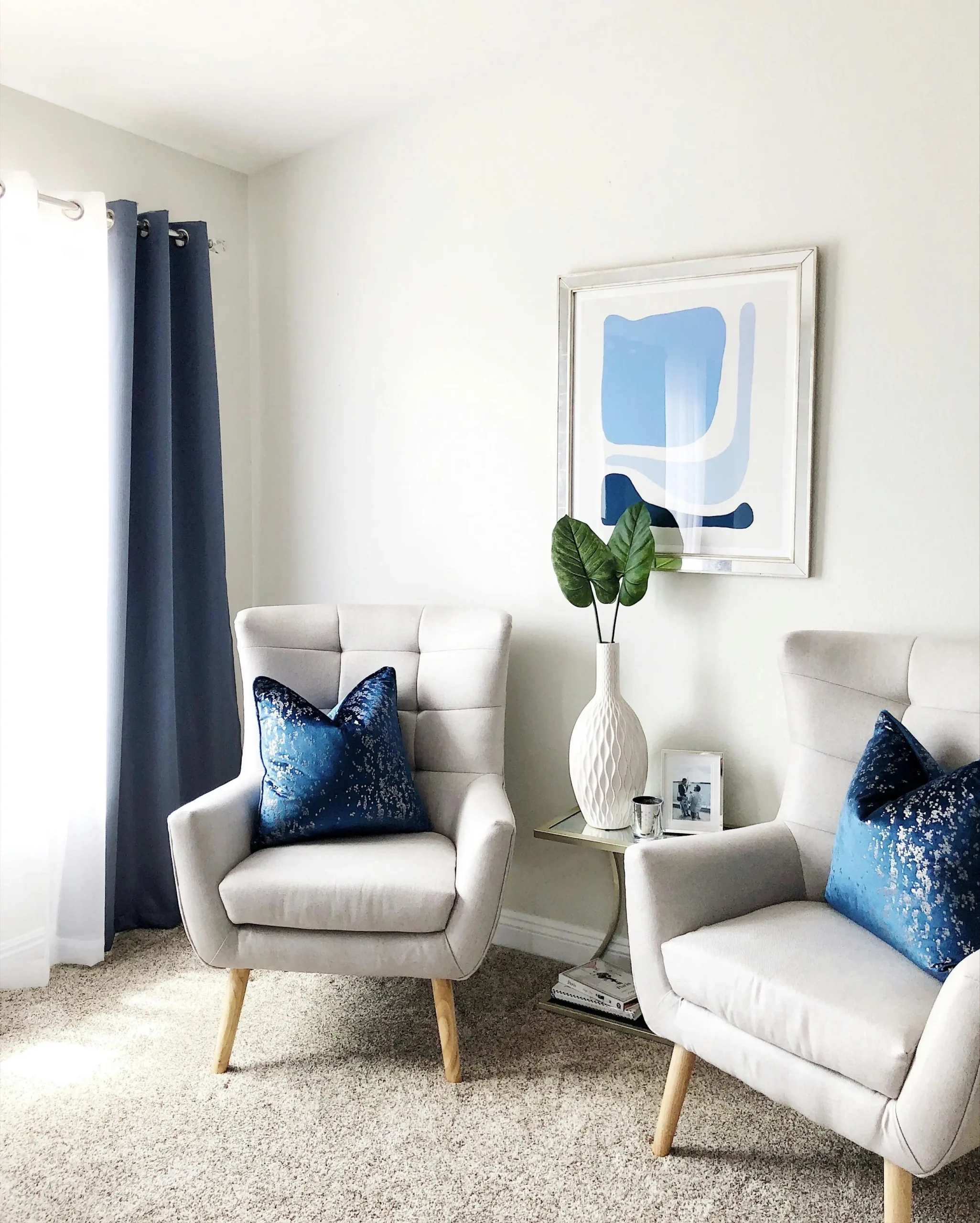 Modern living room in Indiana with two chairs, blue pillows, and abstract art where a dietitian holds nutrition counseling sessions